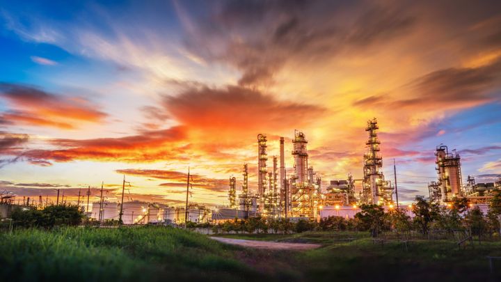 Crude oil refinery with steel pipelines and chimneys at sunset